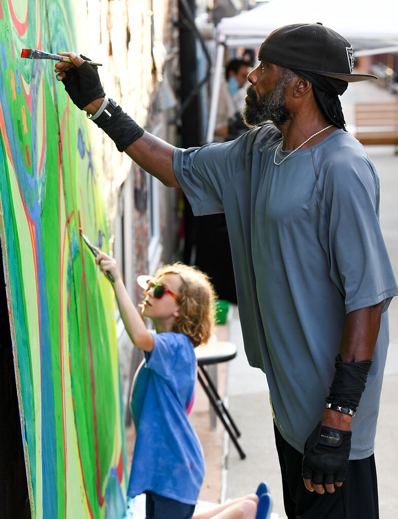 Stephen Turner, right, and Berik Diaz, 8, contribute to the community mural